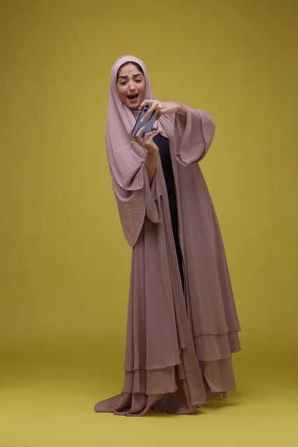 Saudi Woman Playing Mobile Game on Yellow Background