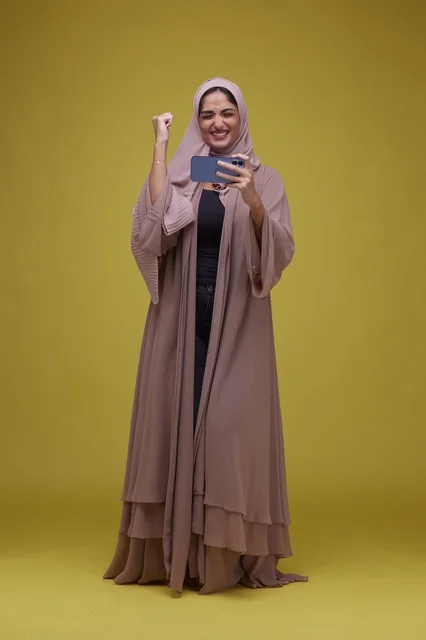 Saudi Woman Playing Mobile Game on Yellow Background