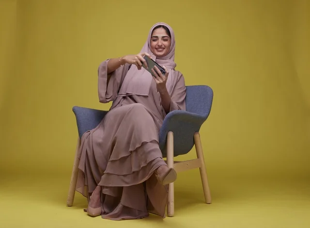 Young Saudi Woman Sitting and Playing Game on Smartphone