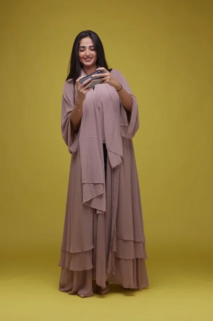 Young Saudi Woman Playing Smartphone Game on Yellow Background