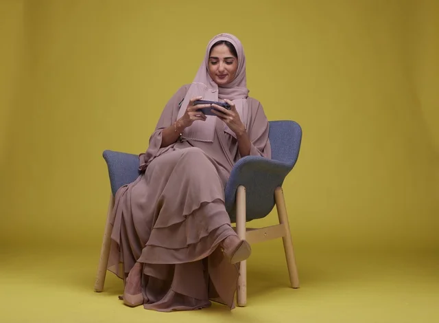 Young Saudi Woman Sitting and Playing Game on Smartphone