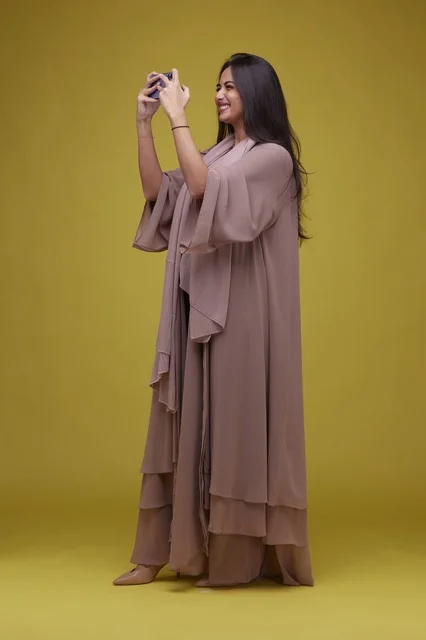 Saudi Woman Playing Smartphone Game on Yellow Background