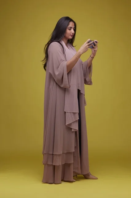 Young Saudi Woman Playing Mobile Game on Yellow Background