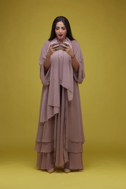 Saudi Woman Playing Mobile Game on Yellow Background