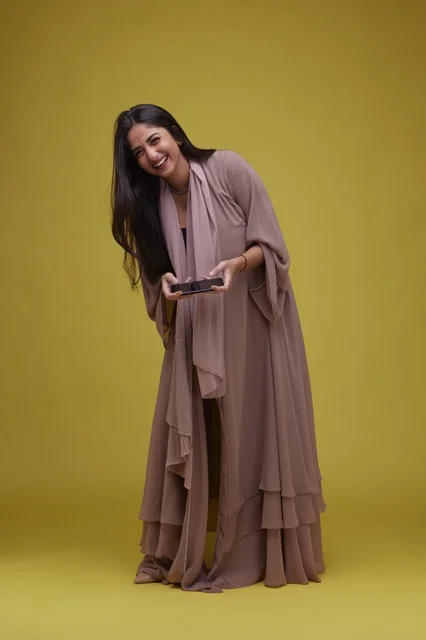 Saudi Woman Playing Smartphone Game on Yellow Background