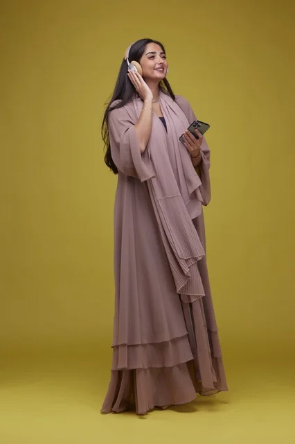 Saudi Woman in Abaya with Headphones and Smartphone