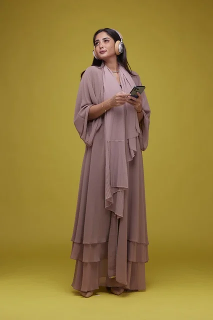 Saudi Woman with Headphones and Smartphone on Yellow Background