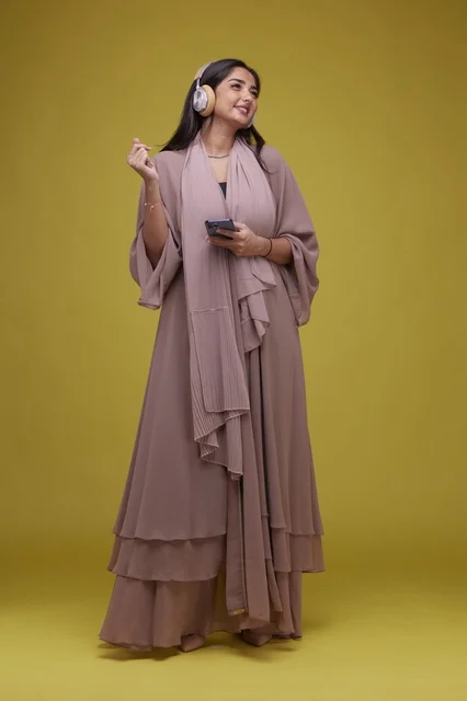 Saudi Woman with Headphones and Smartphone on Yellow