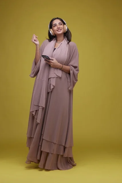 Saudi Woman with Headphones and Smartphone on Yellow Background