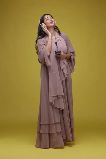 Young Saudi Woman Listening with Headphones and Smartphone
