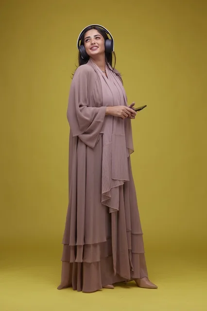 Saudi Woman with Headphones and Phone on Yellow Background