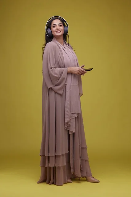 Saudi Woman with Headphones and Smartphone Yellow Background Saudi Woman with Headphones and Smartphone Yellow Background