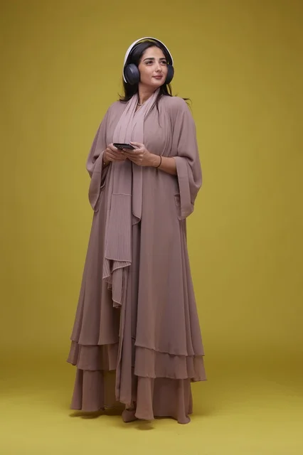 Saudi Woman with Headphones and Smartphone on Yellow Background