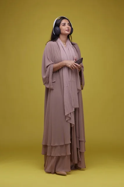Saudi Woman with Headphones and Smartphone Yellow Background