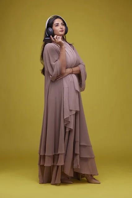 Saudi Woman with Headphones and Smartphone on Yellow
