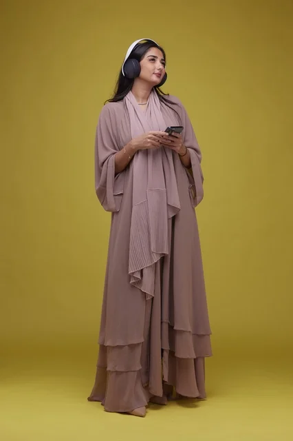 Saudi Woman with Headphones and Smartphone Yellow Background
