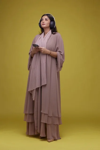 Saudi Woman with Headphones and Smartphone on Yellow