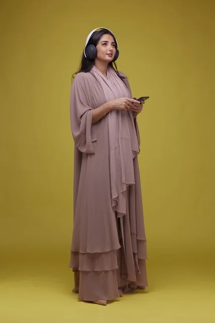 Saudi Woman with Headphones and Smartphone Yellow Background Saudi Woman with Headphones and Smartphone Yellow Background