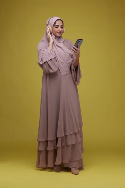 شابة سعودية تستمع للموسيقى بالهاتف الذكي خلفية صفراء
