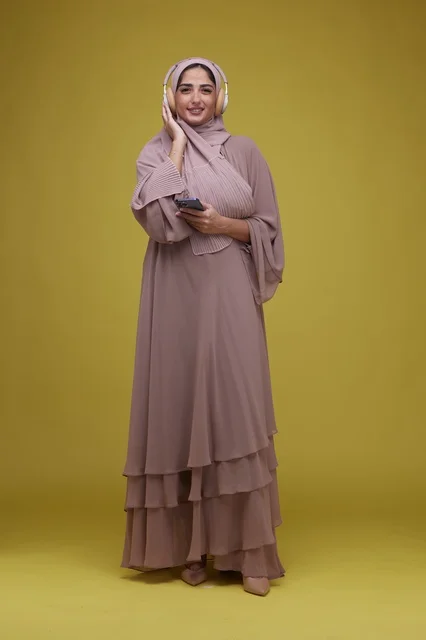 Saudi Woman with Headphones and Smartphone on Yellow