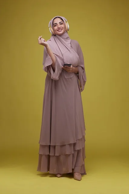 Saudi Woman with Headphones and Smartphone on Yellow Background