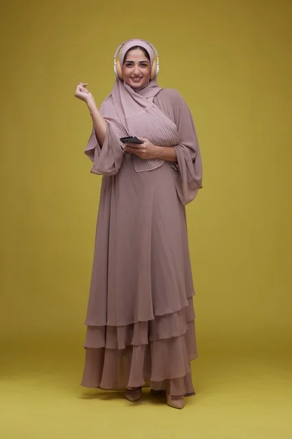 Saudi Woman with Headphones and Smartphone on Yellow Background