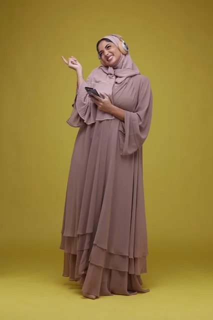 Saudi Woman with Headphones and Smartphone on Yellow
