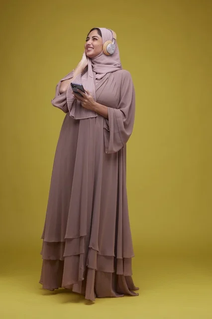 شابة سعودية تستخدم سماعات الرأس والهاتف الذكي