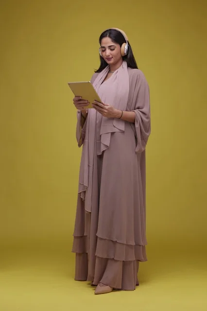 Saudi Woman Using Tablet with Headphones on Yellow Background