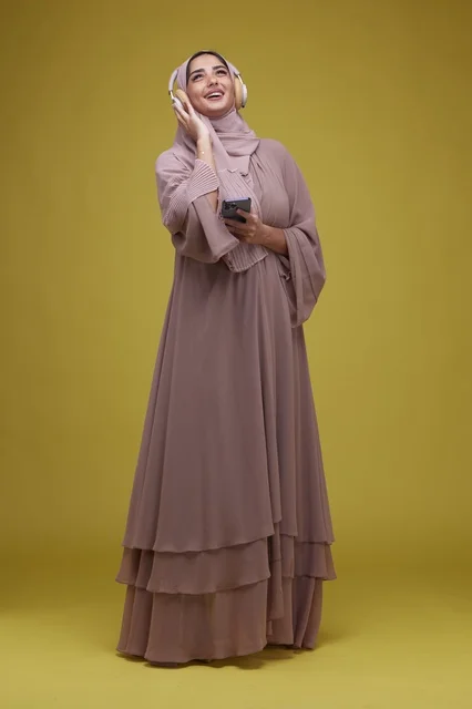 Saudi Woman with Headphones and Smartphone on Yellow