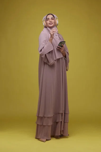 Saudi Woman with Headphones and Smartphone on Yellow