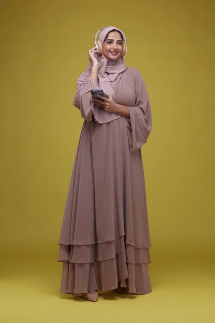 امرأة سعودية تستمع للموسيقى بالهاتف أمام خلفية صفراء