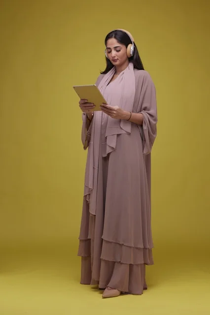 Saudi Woman with Tablet and Headphones on Yellow Background