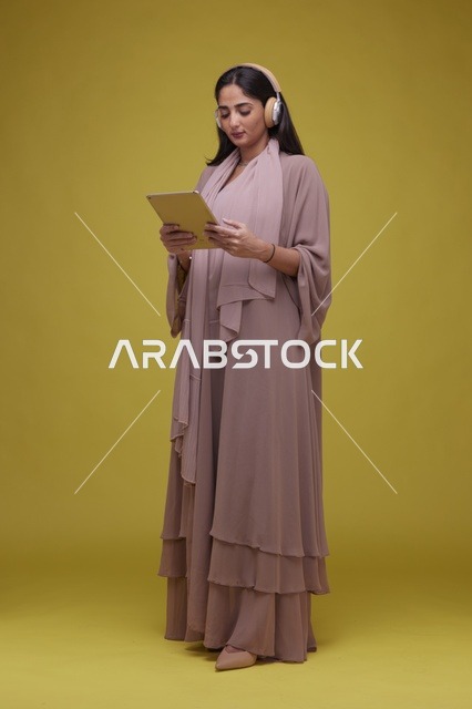 شابة سعودية تستخدم جهاز لوحي مع سماعات رأس