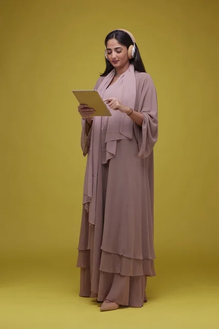 Saudi Woman Using Tablet and Headphones in Yellow Studio
