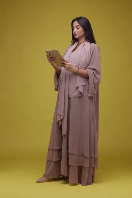 Saudi Woman Using Digital Tablet on Yellow Background