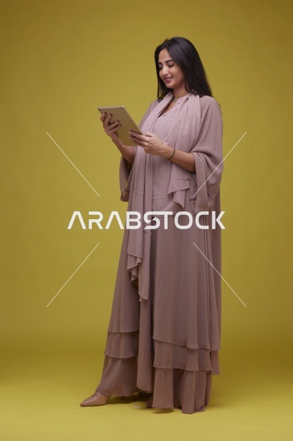 شابة سعودية تستخدم جهاز لوحي بخلفية صفراء
