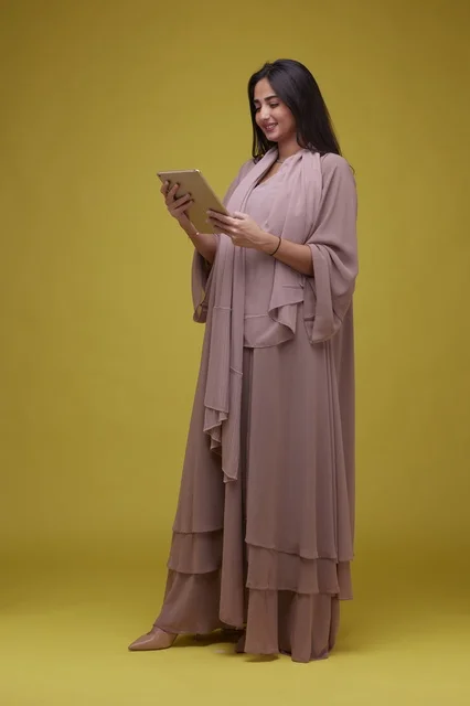 Saudi Woman Using Digital Tablet on Yellow Background