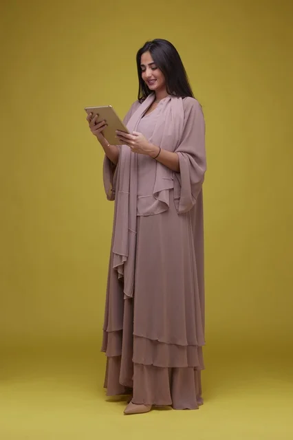 Saudi Woman Using Tablet on Yellow Background