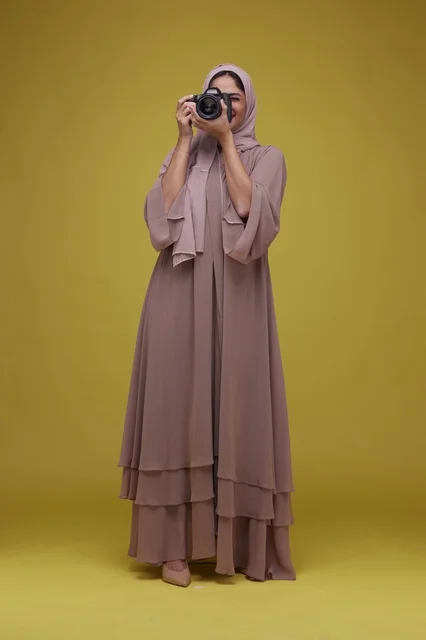Saudi Woman Photographer with DSLR Camera on Yellow Background Saudi Woman Photographer with DSLR Camera on Yellow Background