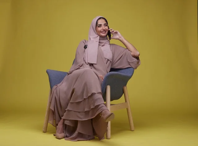 Saudi Woman Talking on Smartphone on Yellow Background