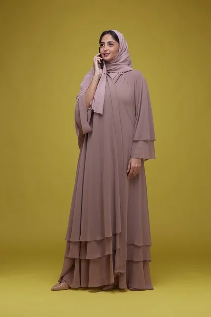 امرأة سعودية تتحدث بالهاتف الذكي بعباية بيج داخل استوديو