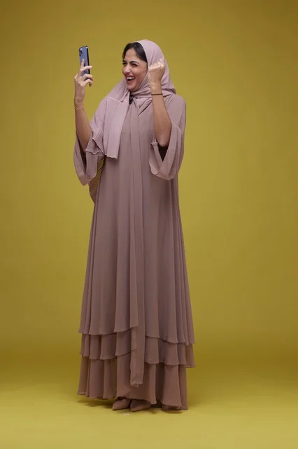Saudi Woman with Smartphone Celebrating on Yellow Background