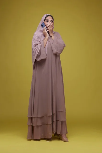 Surprised Saudi Woman with Smartphone in Beige Abaya