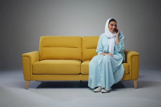 Saudi Woman Talking on Smartphone on Yellow Sofa