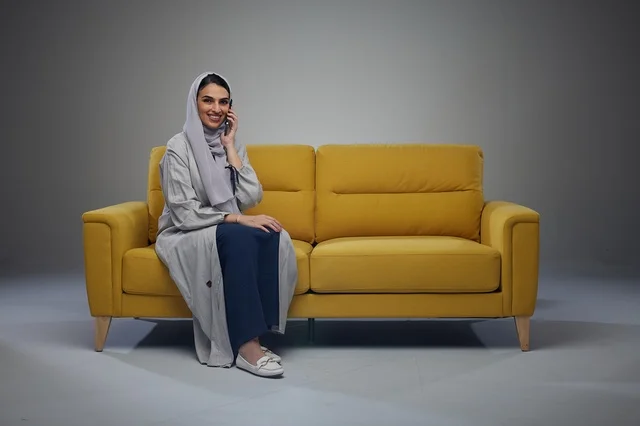 Saudi Woman Talking on Smartphone on Yellow Sofa