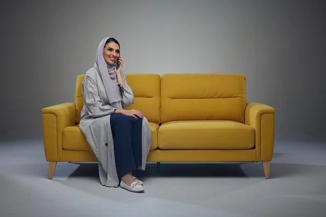 Saudi Woman Talking on Smartphone on Yellow Sofa
