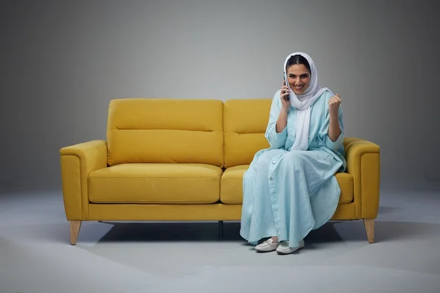 Saudi Woman on Yellow Sofa Using Smartphone