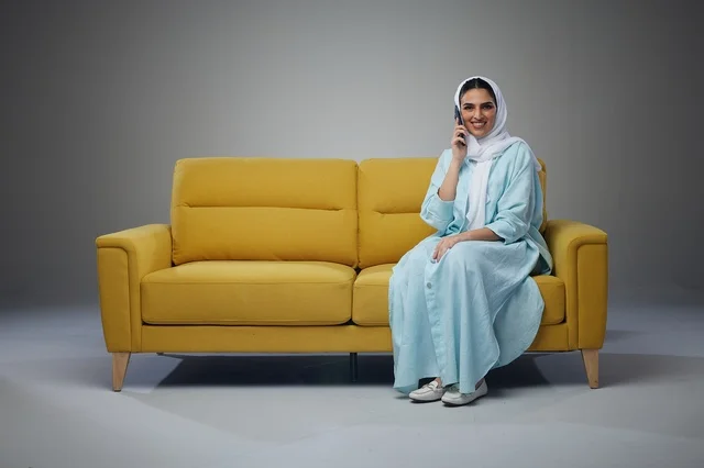 Saudi Woman on Yellow Sofa Talking on Smartphone