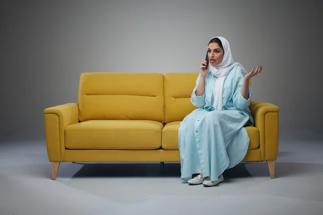 Saudi Woman on Yellow Sofa Talking on Smartphone